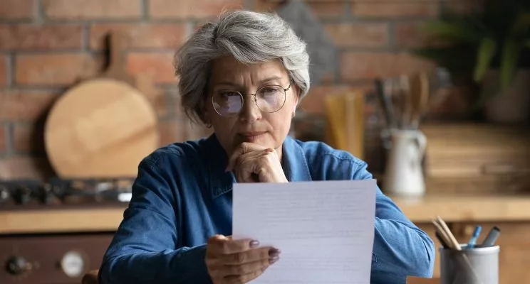 thought middle aged woman 60s with glasses looking at paper